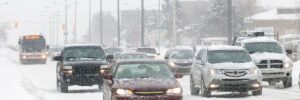 Cars driving in winter weather conditions with snow on the ground.