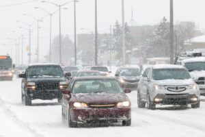 Cars driving in winter weather conditions with snow on the ground.